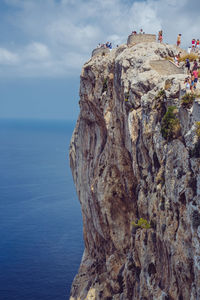 People at the edge of mountain by sea