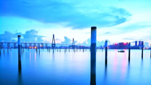 Wooden posts in lake against sky