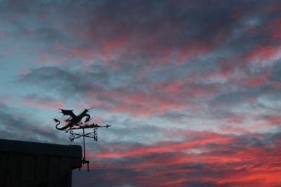 Silhouette of weather vane against cloudy sky