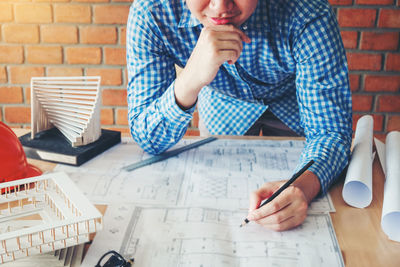 Midsection of man holding paper while sitting on table