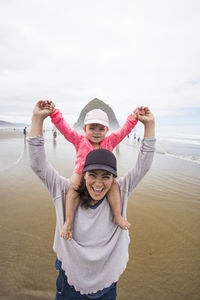 Portrait of happy friends on beach against sky