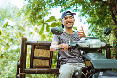 Young man using mobile phone while sitting on bench in park