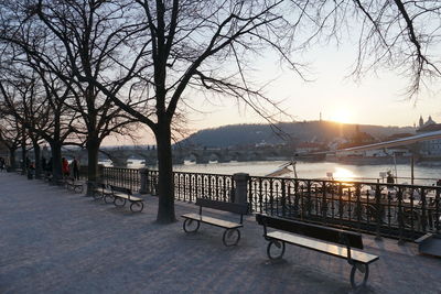 Empty bench by river in city during winter