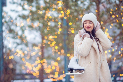 Portrait of young woman standing against trees during winter