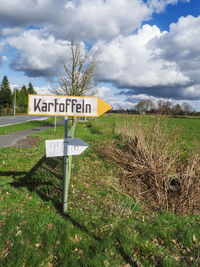 Information sign on field against sky