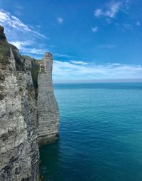 Rock formation in sea against blue sky