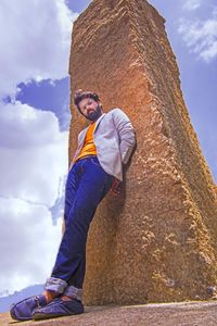 Low angle view of young man standing against rock formation