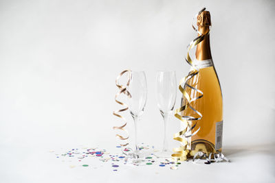 Two empty glasses and bottle of champagne against white background.
