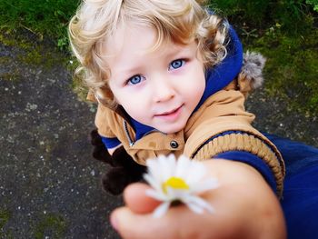 Portrait of cute boy holding daisy