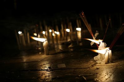 Candles and incense sticks burning on street at night