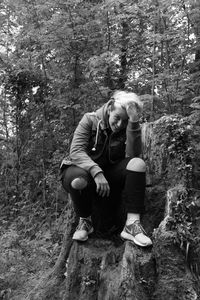 Full length of boy sitting on tree trunk