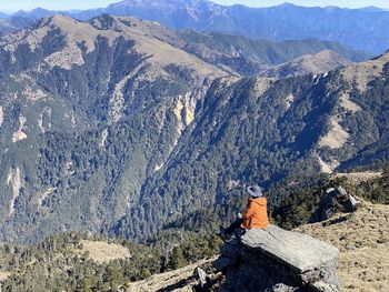 Rear view of man sitting on mountain