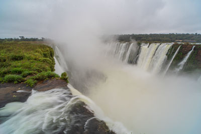 Scenic view of waterfall against sky