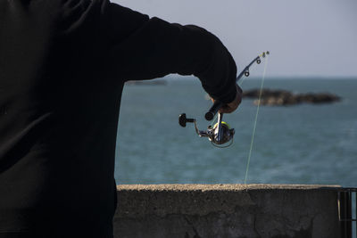 Midsection of man fishing at sea