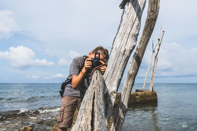 Man photographing on sea against sky