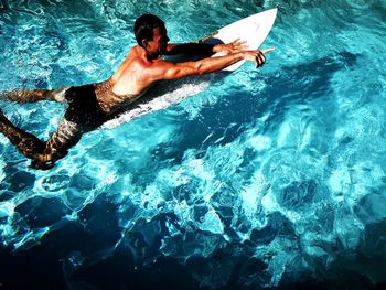 Wide angle view of man swimming in pool with surfboard