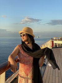 Woman wearing hat against sea against sky