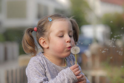 Close-up of girl blowing dandelion seeds