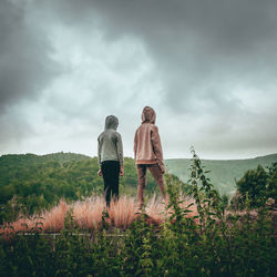 Rear view of women standing on field against sky