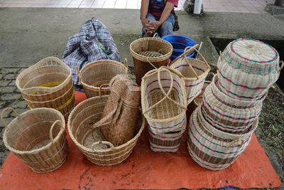 Midsection of woman sitting by baskets for sale at market