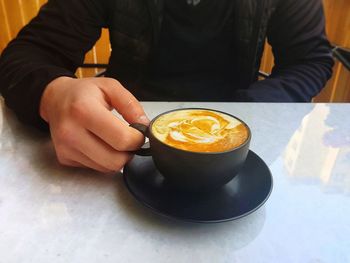 Midsection of man holding coffee cup