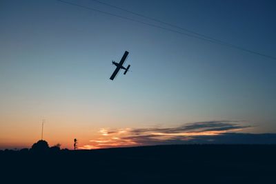 Low angle view of silhouette helicopter against sky during sunset