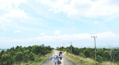 Man riding motorcycle on road against sky