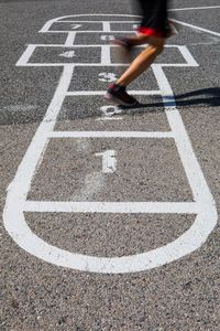Low section of person playing hopscotch on road