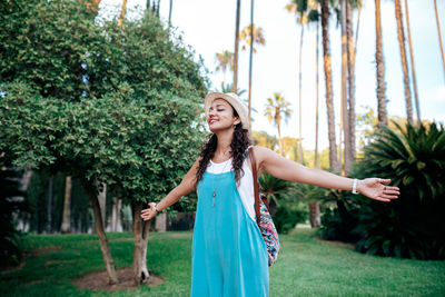 Smiling young woman standing by plants