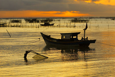 Silhouette fishing boats in sea against sky during sunset