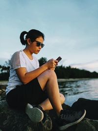 Young girl using mobile phone while sitting on water