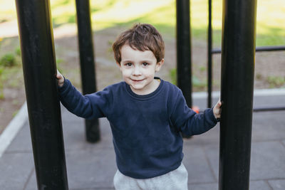 Portrait of smiling boy standing against fence