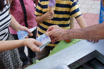 Midsection of woman giving paper currency to shopkeeper