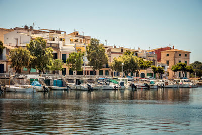 Boats moored in river by buildings against clear sky