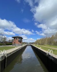 Canal amidst houses against sky