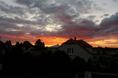 Houses against cloudy sky at sunset