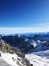 Scenic view of snowcapped mountains against blue sky