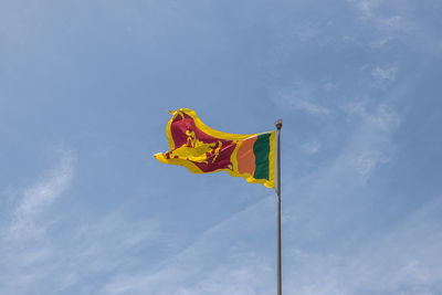 Low angle view of sri lankan flag against cloudy sky