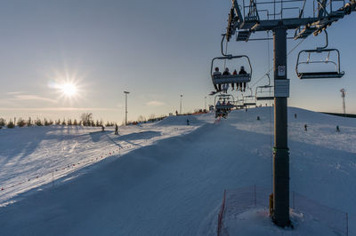 Snow covered ski lift against sky during winter