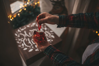 Midsection of man holding christmas decoration at home