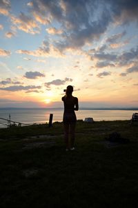 Silhouette woman standing on beach against sky during sunset