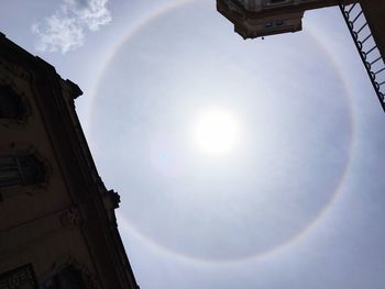 Low angle view of sun shining through clouds