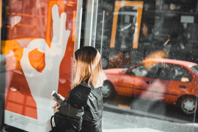 Woman using mobile phone while standing in city