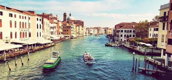 Boats in canal amidst buildings in city against sky