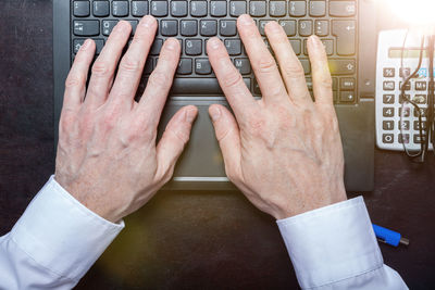 Cropped hands of businessman using laptop at desk