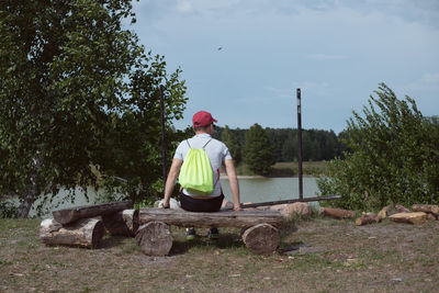 Rear view of man sitting on seat against lake