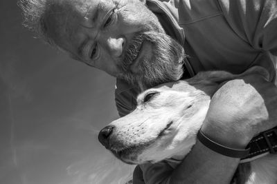 Mature man with beard hugging his old beagle dog