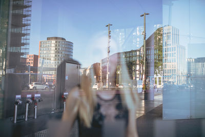 Woman looking through glass window with city reflection 