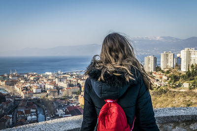 Rear view of woman standing by sea against clear sky