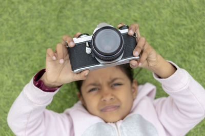 Portrait of cute girl photographing with camera on grassy field